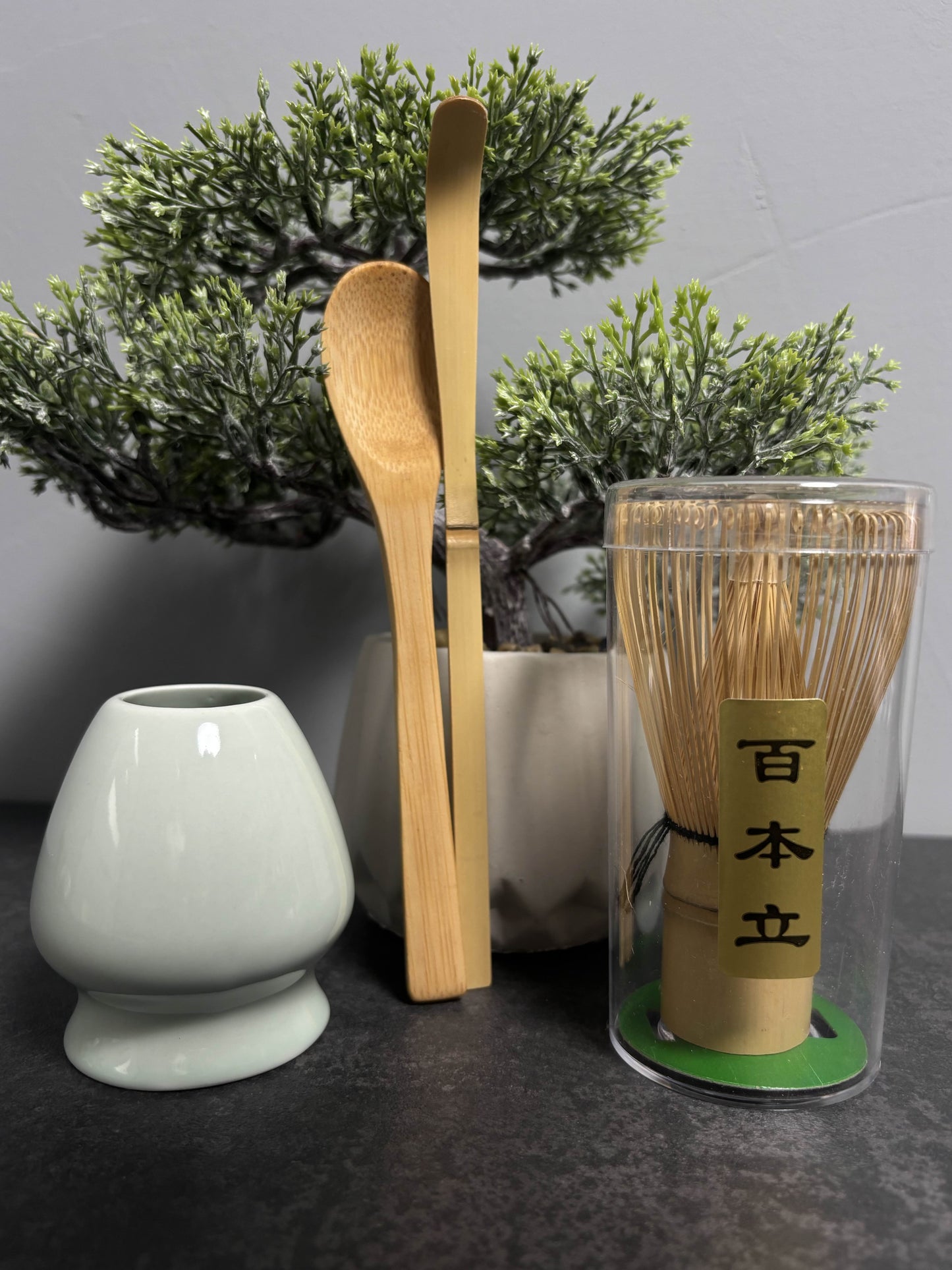 Prémium matcha tea szett bambusz ecsettel, tálkával és adagolókanállal, természetes környezetben fotózva.