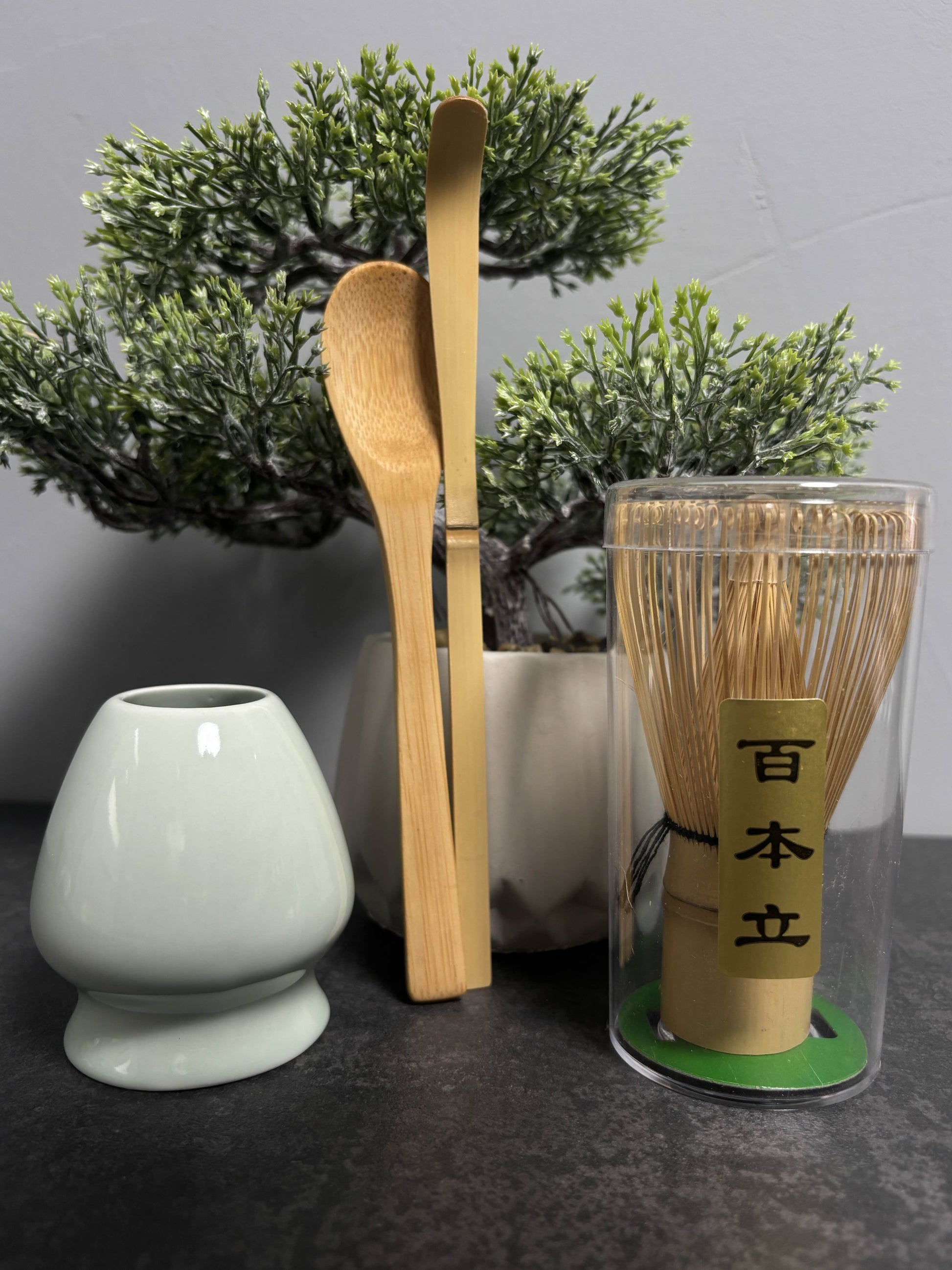 Prémium matcha tea szett bambusz ecsettel, tálkával és adagolókanállal, természetes környezetben fotózva.